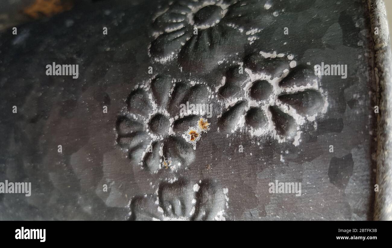 Floral pattern forged ornament of rough grey metal surface closeup. Metallic flowers on steel texture Stock Photo