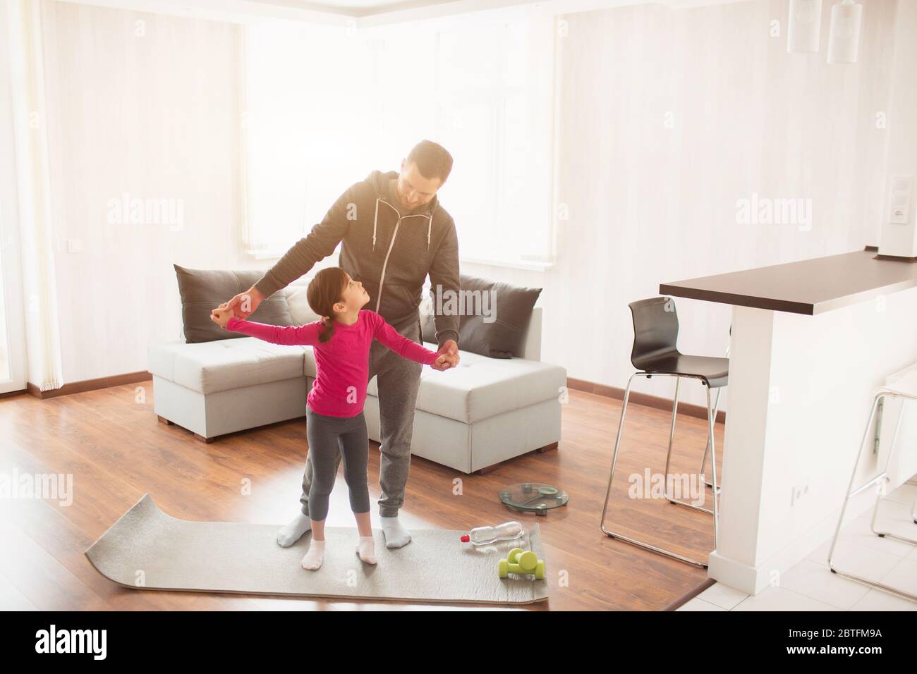 father and daughter are training at home. Workout in the apartment. Sports at home. They are standing on a yoga mat Stock Photo