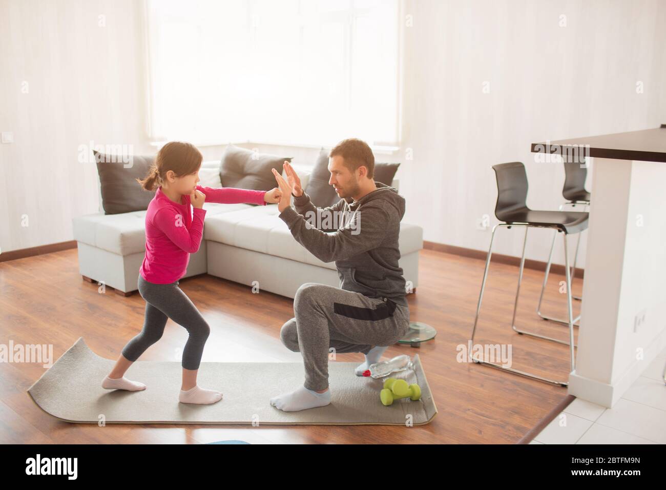 father and daughter are training at home. Workout in the apartment. Sports at home. Father teaches to keep a punch. Boxing together. Boxing training a Stock Photo