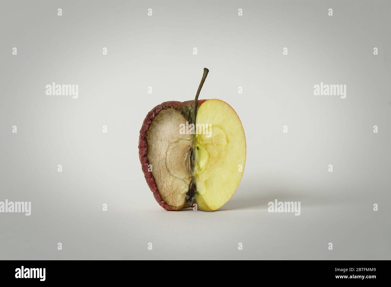 red apple with one half good and the other half rotten, concept of time, fruit that becomes garbage and that is thrown away, white background, isolate Stock Photo