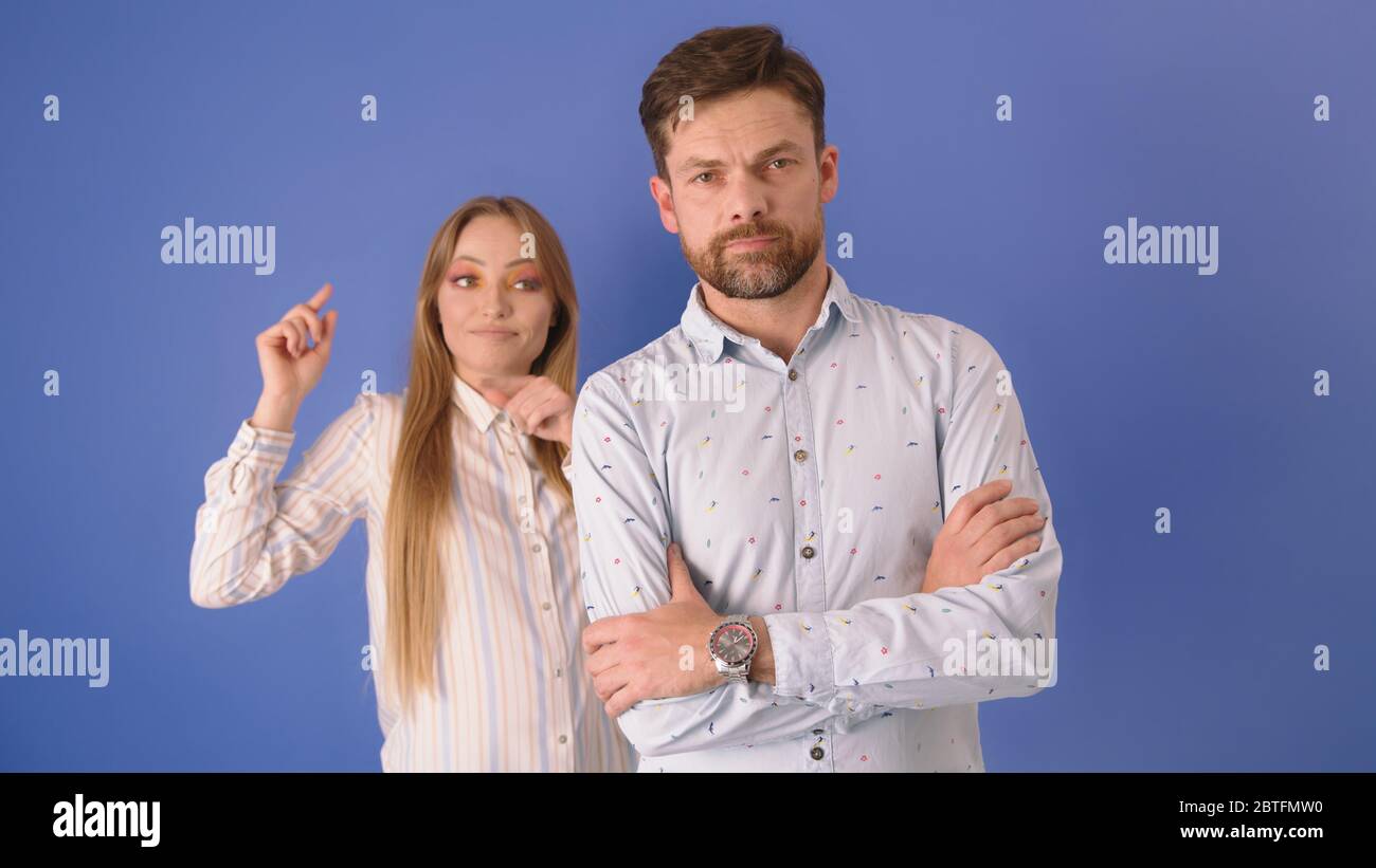 Man and the woman isolated on the blue background. Woman using sign ...