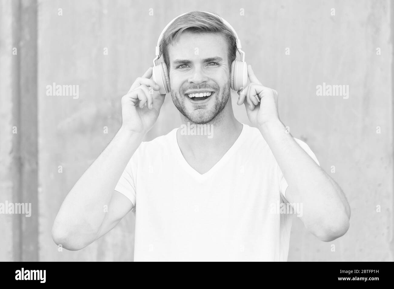 Wireless Earpiece. Handsome guy wear headphones grey background. Man listen modern music. Modern technology. Hobby leisure. Foldable Stereo Headphones. Noise Reduction. Modern and contemporary music. Stock Photo