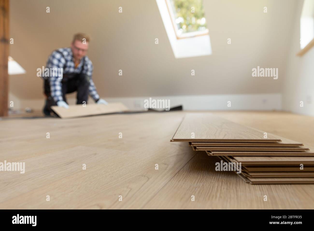 Construction worker installing laminate floor in a new renovated attic. Home improvement concept. Stock Photo