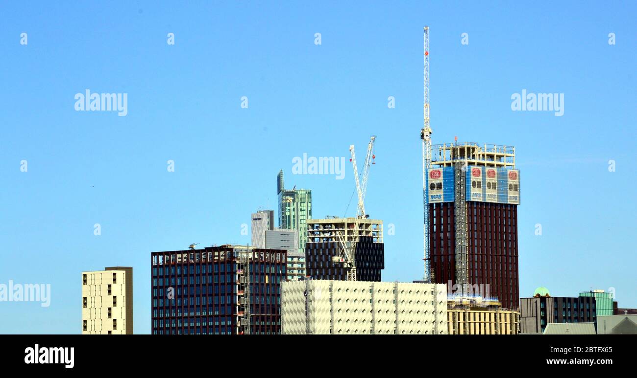 Construction of high rise buildings with tower cranes in central Manchester, England, United Kingdom, against a blue sky Stock Photo
