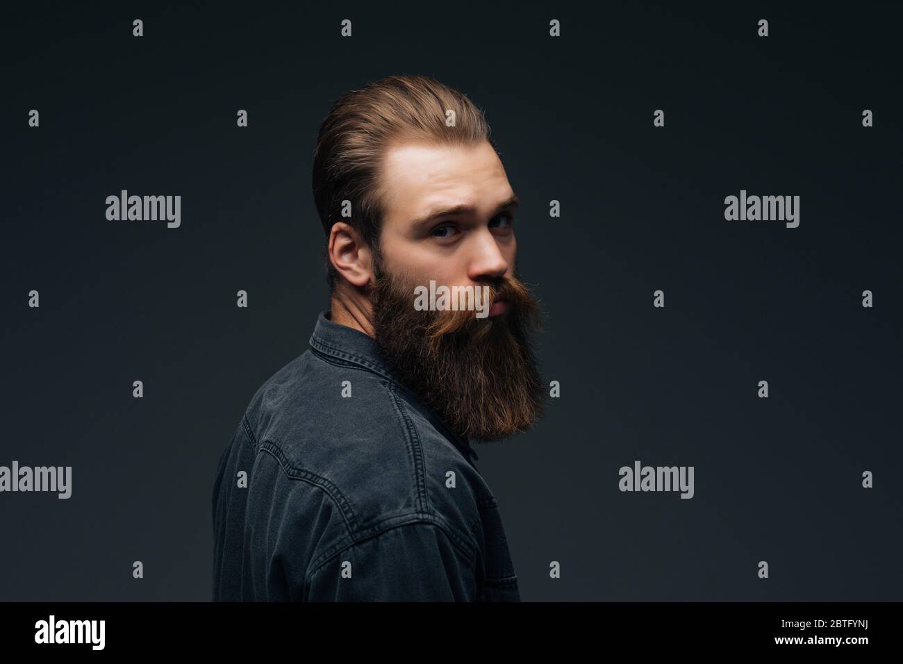 Handsome bearded young man isolated on gray background Stock Photo