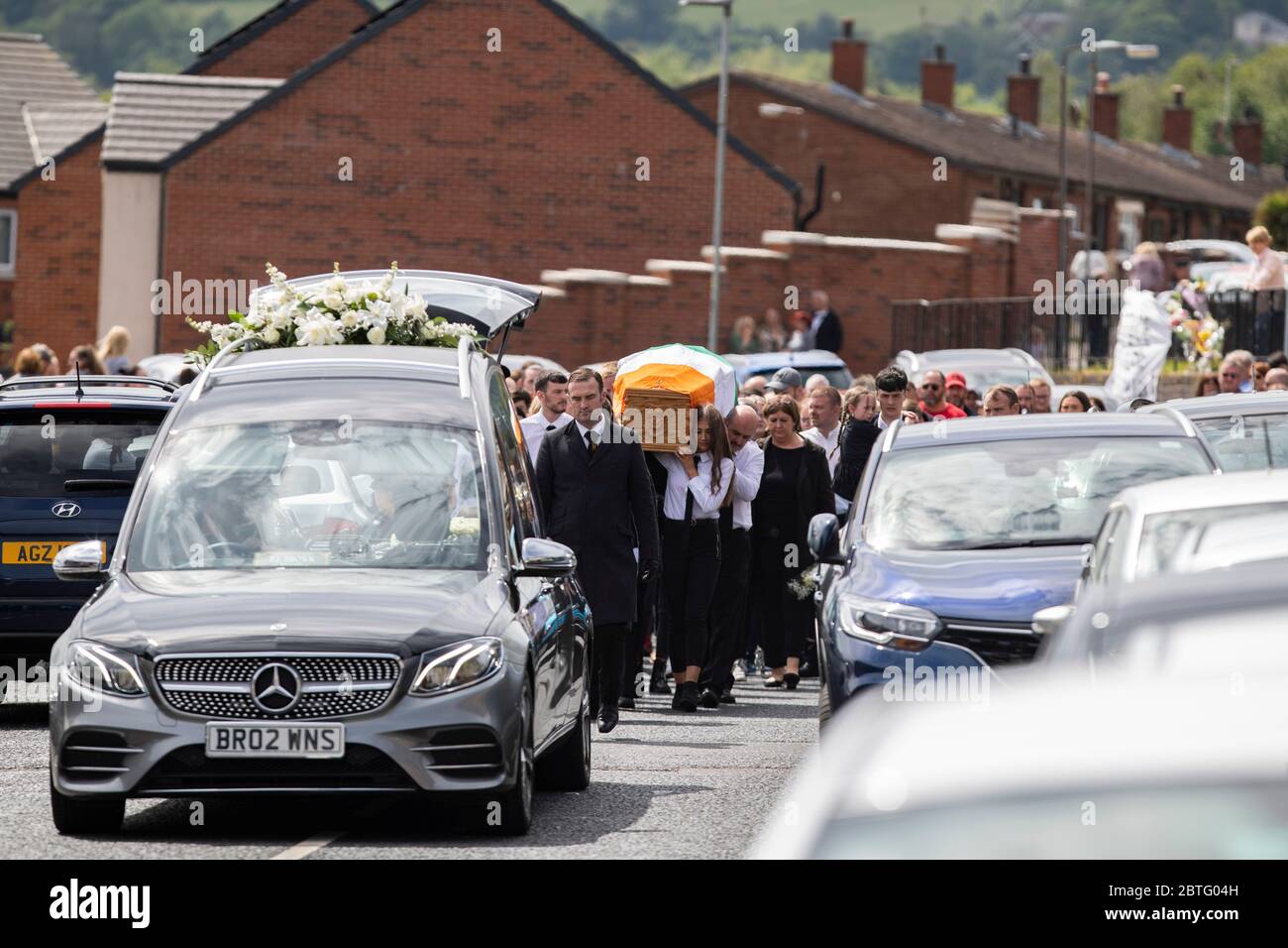 Lenadoon, West Belfast, Northern Ireland. 25th May, 2020. Mourners gather outside the home of Kieran Wylie (57) who was shot dead in Lenadoon, West Belfast as his remains are carried out of his home. Mr Wylie was believed to have been murdered over informing on Dissident Terrorist Groups in Northern Ireland Credit: Conor Kinahan/Alamy Live News Stock Photo