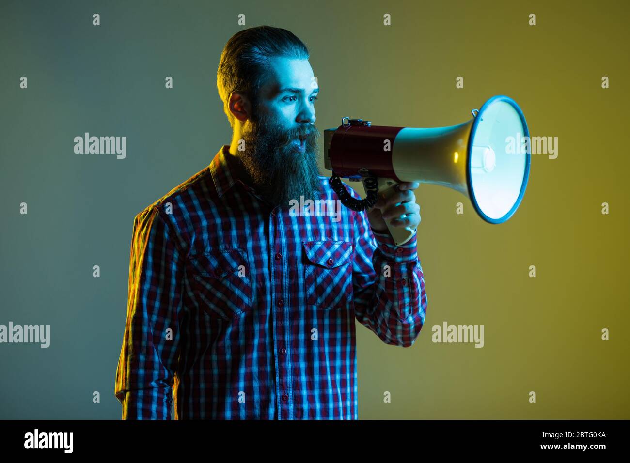 Young hipster man shouting by megaphone on yellow background Stock ...