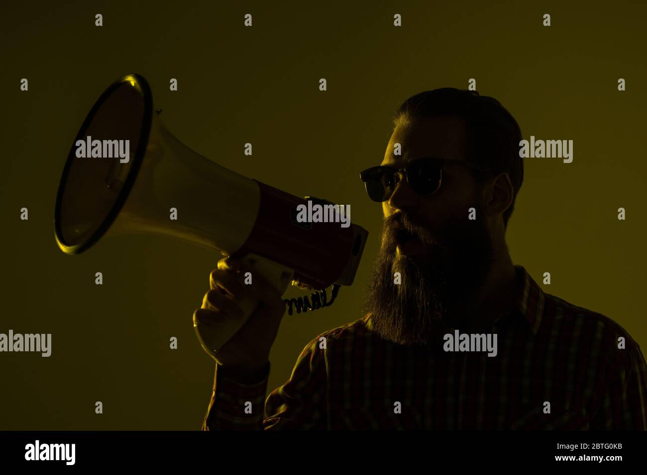 Young hipster man shouting by megaphone on yellow background Stock ...