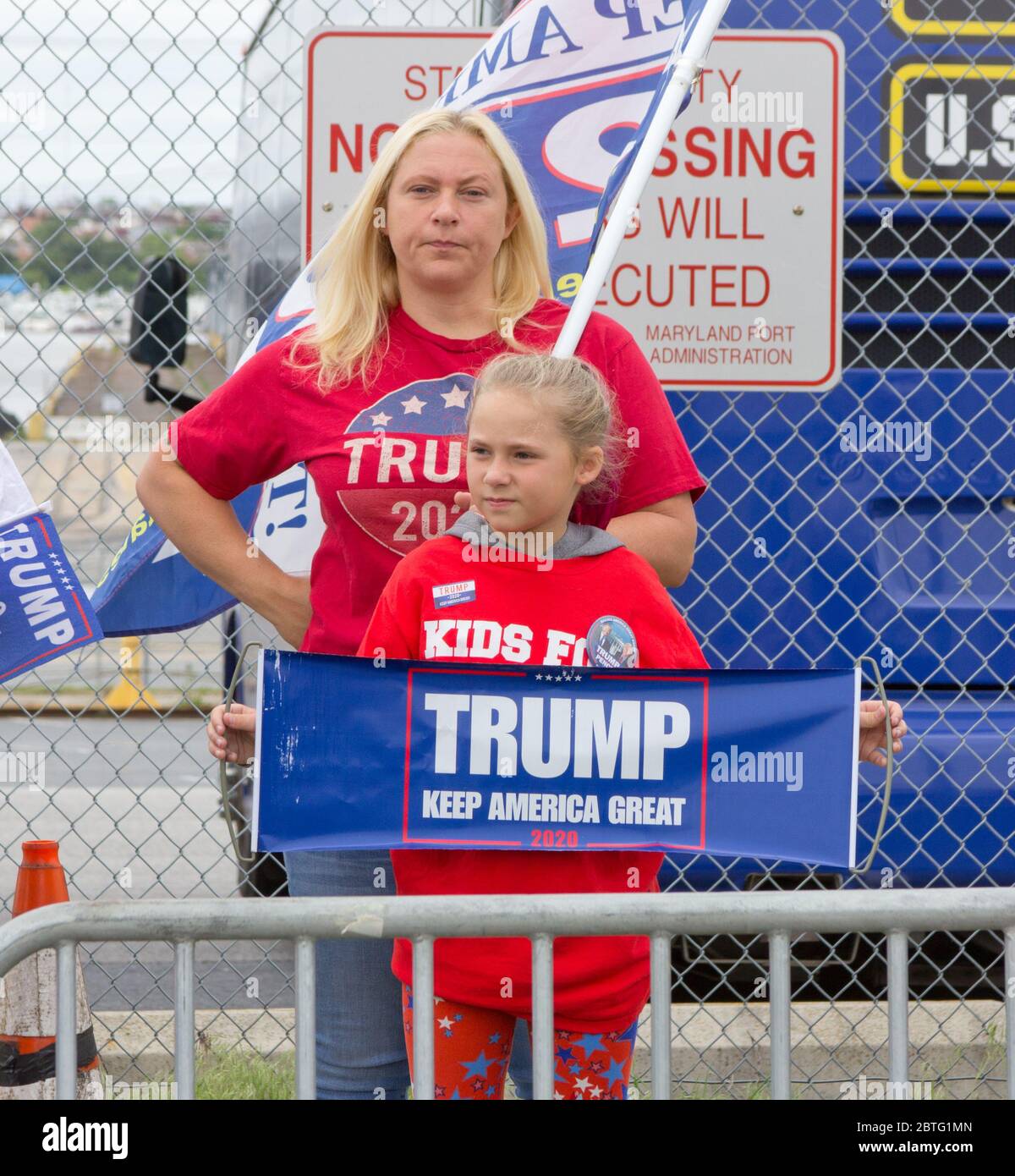 Baltimore, Maryland, USA. 25th May, 2020. Woman and young girl stand with pro-Trump clothing and signs behind barricade outside historic Fort McHenry in Baltimore, Maryland, where President Donald Trump and First Lady Melania Trump visit on Memorial Day 2020 despite urging from Baltimore Mayor Bernard C. “Jack” Young to cancel to avoid setting a bad example while the city remains under a stay-at-home order (with exemptions including some outdoor exercise), and to avoid being an expensive drain on public safety resources. Girl wears t-shirt reading 'Kids For Trump'. Kay Howell/Alamy Live News Stock Photo