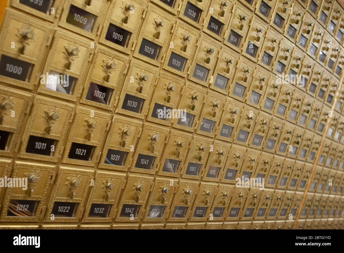 Row of vintage brass pigeonhole mailboxes with doors and combination locks in a mail room Stock