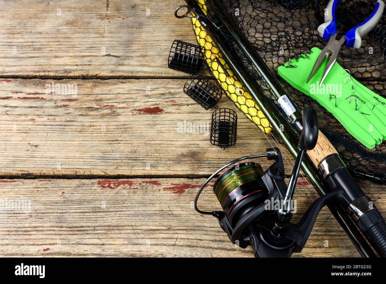 Fishing tackle. Fishing rod, fishing hooks, landing net and pliers on old  wooden background with free space for text Stock Photo - Alamy