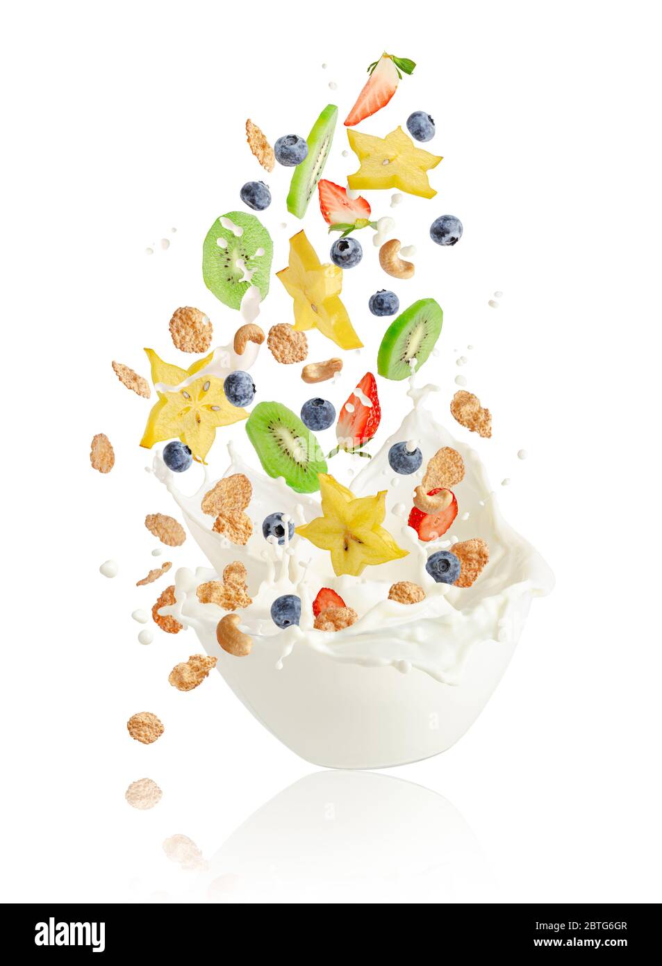 Fresh fruits, berries, corn flakes and nuts falling into the bowl with splashing milk. Healthy