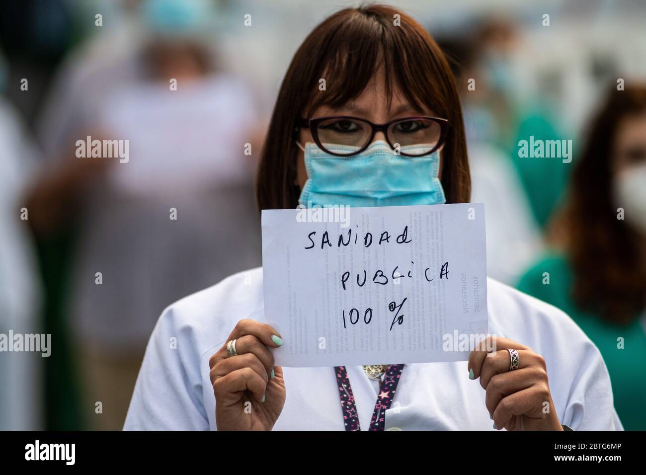 Madrid, Spain. 25th May, 2020. Healthcare worker showing a placard that reads: Health care 100% public, in 12 de Octubre Hospital. Healthcare workers carry out the first protest during the coronavirus crisis against the precariousness of their work as Madrid has entered the so-called Phase One transition from the coronavirus lockdown. Credit: Marcos del Mazo/Alamy Live News Stock Photo