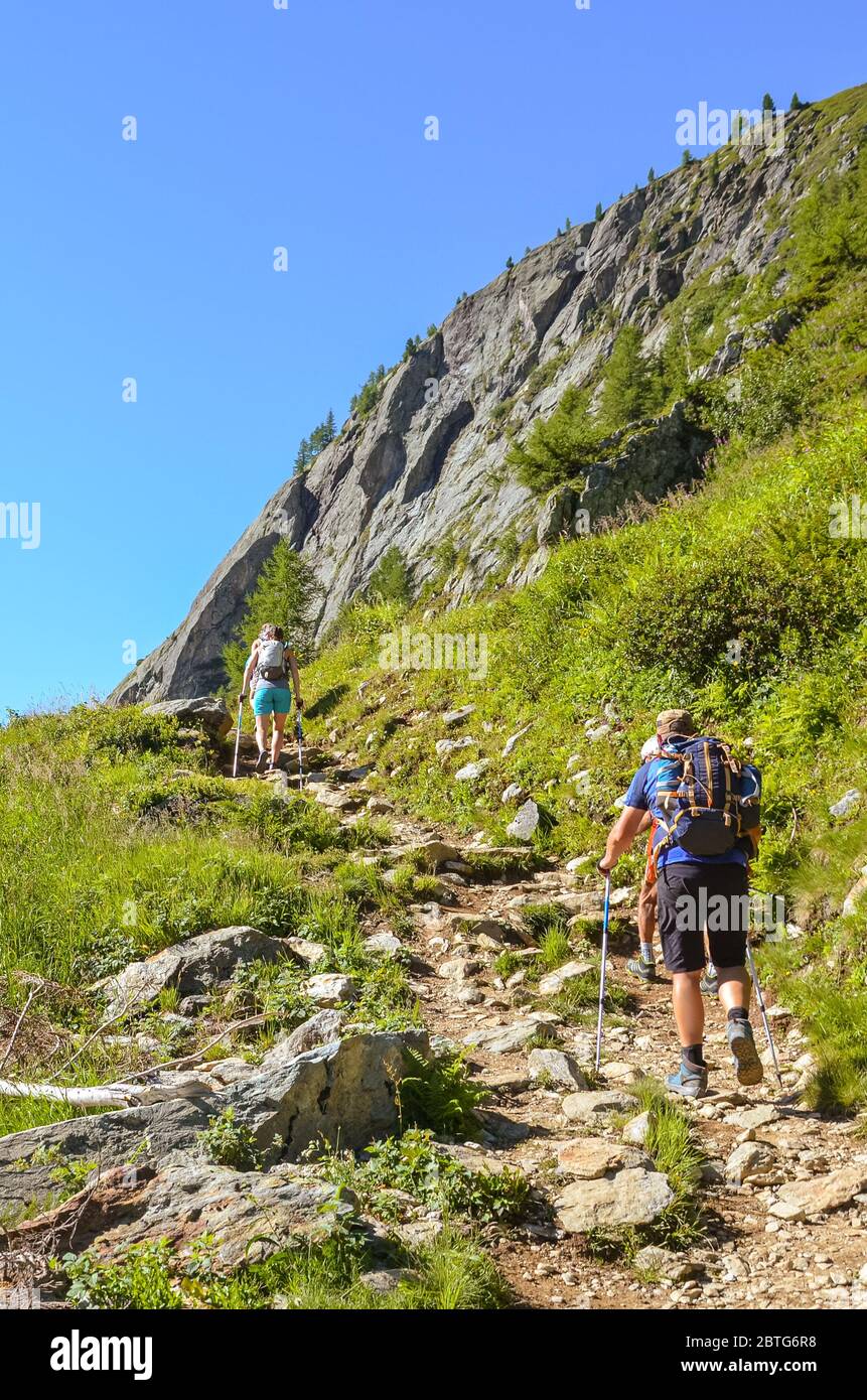 Hikers with hiking poles in French Alps near Chamonix on a trail to Lac Blanc with Mont Blanc view. Beautiful Alpine landscape in France. People with walking sticks. Alps in summer. Active vacation. Stock Photo
