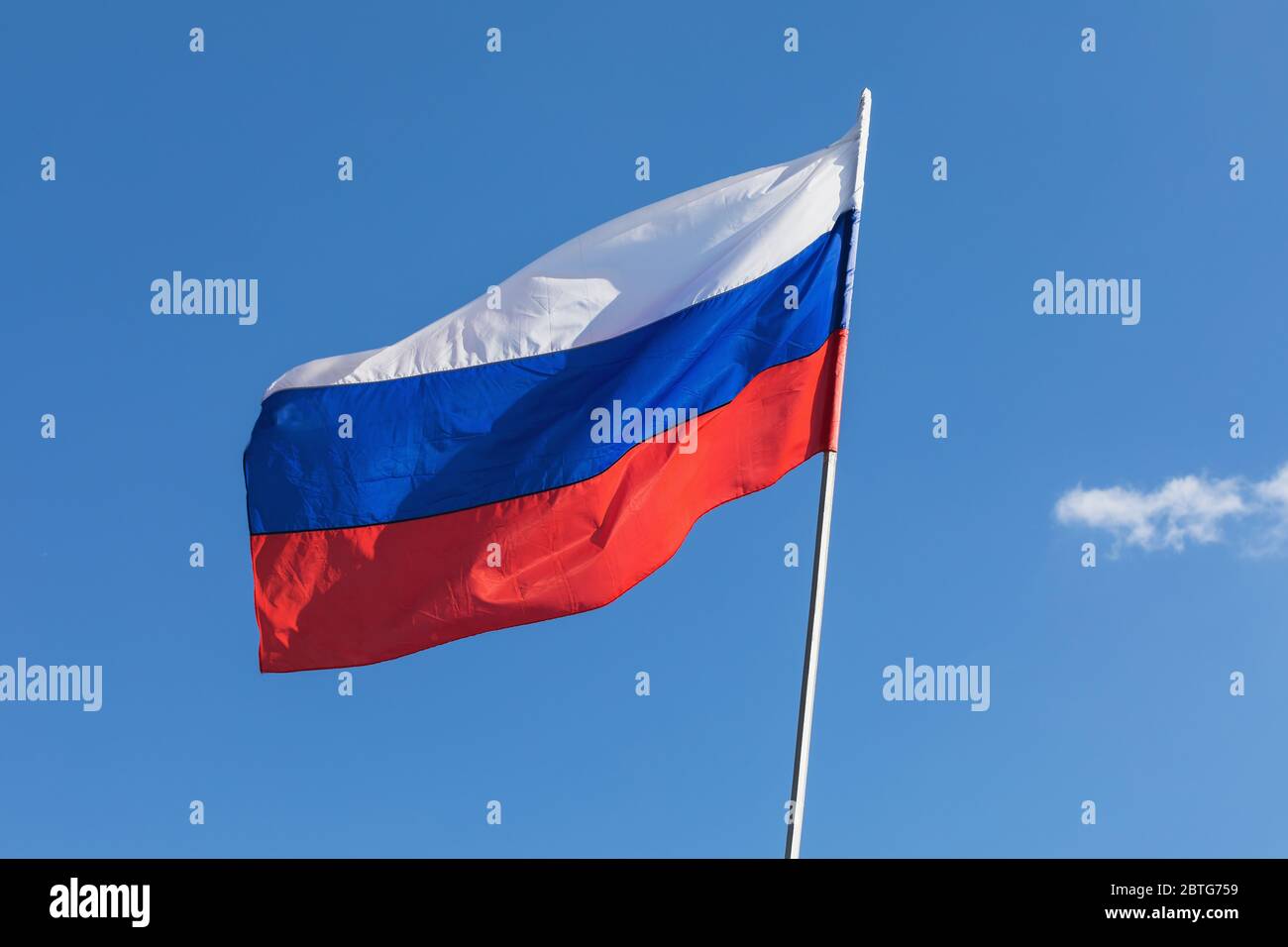 Flag of Russia developing against the blue sky Stock Photo