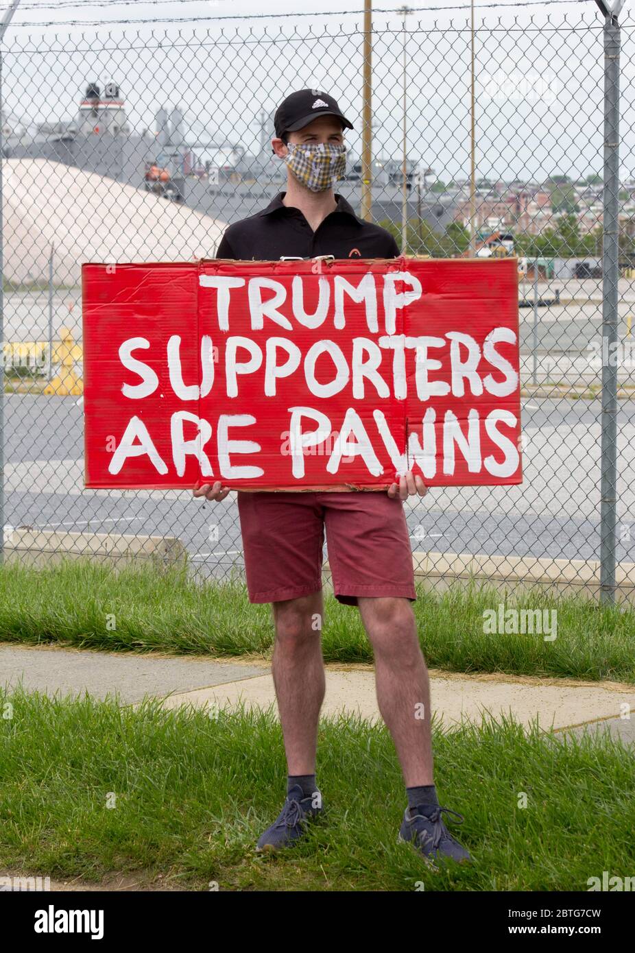Baltimore, Maryland, USA. 25th May, 2020. Man with protective face mask holds sign reading 'Trump Supporters Are Pawns' outside historic Fort McHenry in Baltimore, Maryland, where President Donald Trump and First Lady Melania Trump visit on Memorial Day 2020 despite urging from Baltimore Mayor Bernard C. “Jack” Young to cancel to avoid setting a bad example while the city remains under a stay-at-home order (with exemptions including some outdoor exercise), and to avoid being an expensive drain on public safety resources. Kay Howell/Alamy Live News Stock Photo