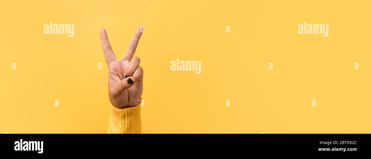 Hand gesture V sign for victory or peace sign over yellow background ...