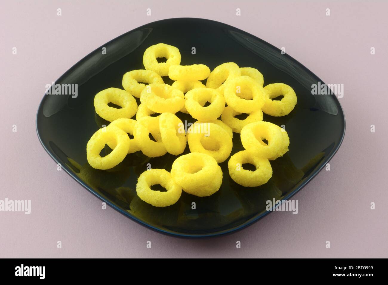 Pickled onion rings corn snacks on dark blue square plate on lavender  background Stock Photo - Alamy