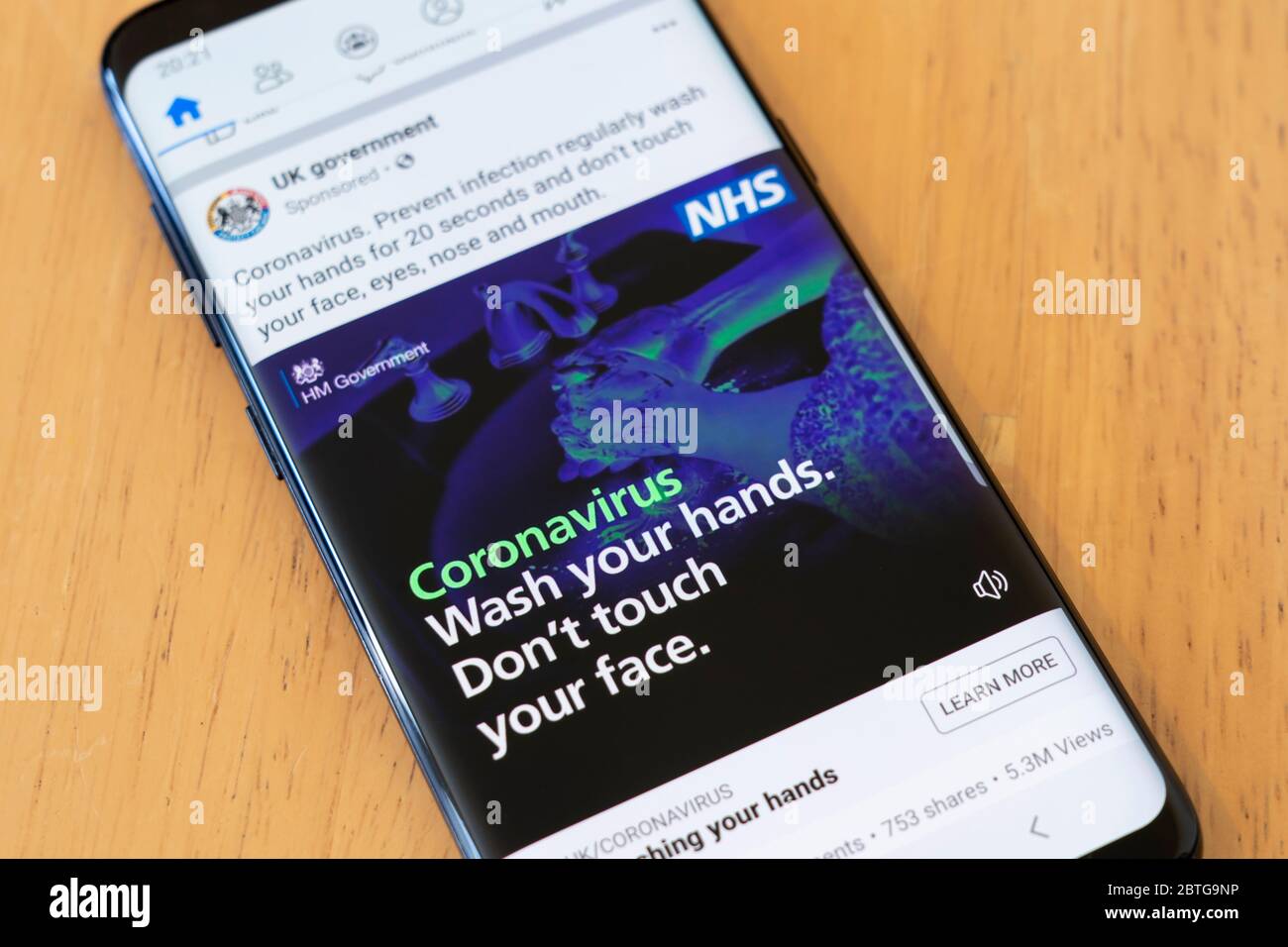 An advertisement from UK Government on a smartphone screen warning the British public to Wash your hands. Don't touch your face. Covid 19 Coronavirus Stock Photo