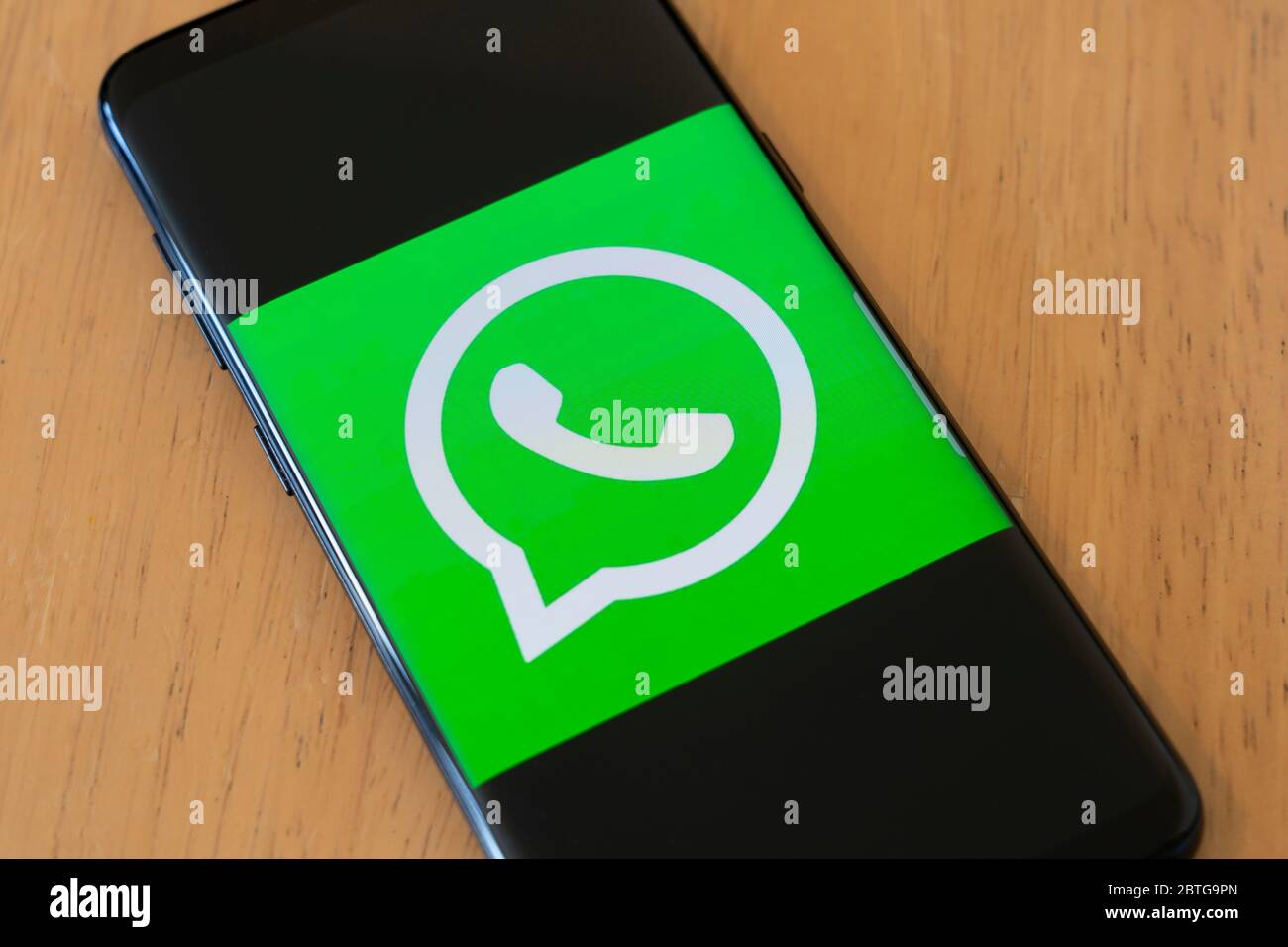 A large logo for the video calling and media sharing social media app WhatsApp on a smartphone screen Stock Photo