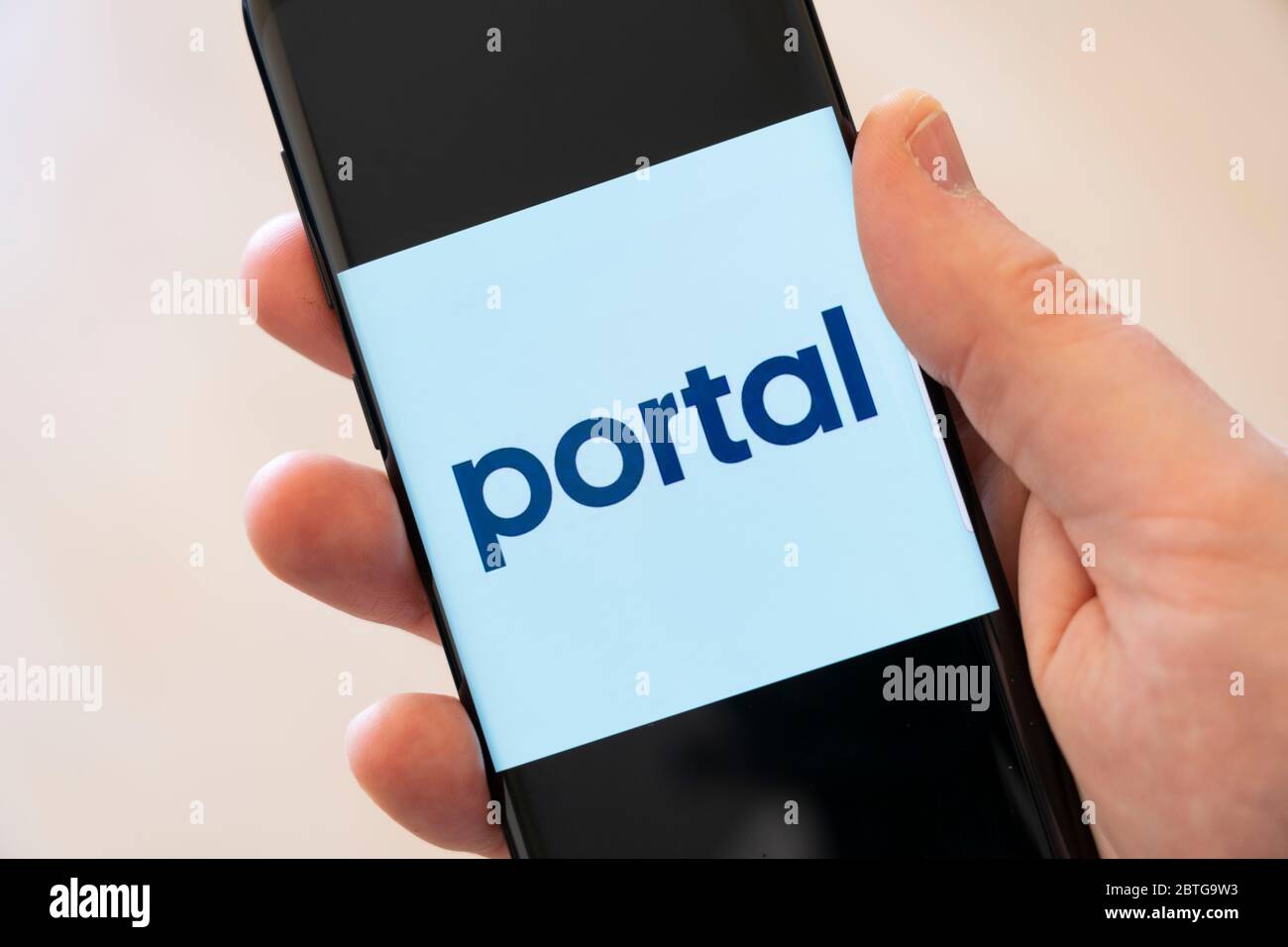 A man's hand holding a cell phone displaying a large logo for the Portal App by Facebook that lets you control Portal devices with your smartphone Stock Photo