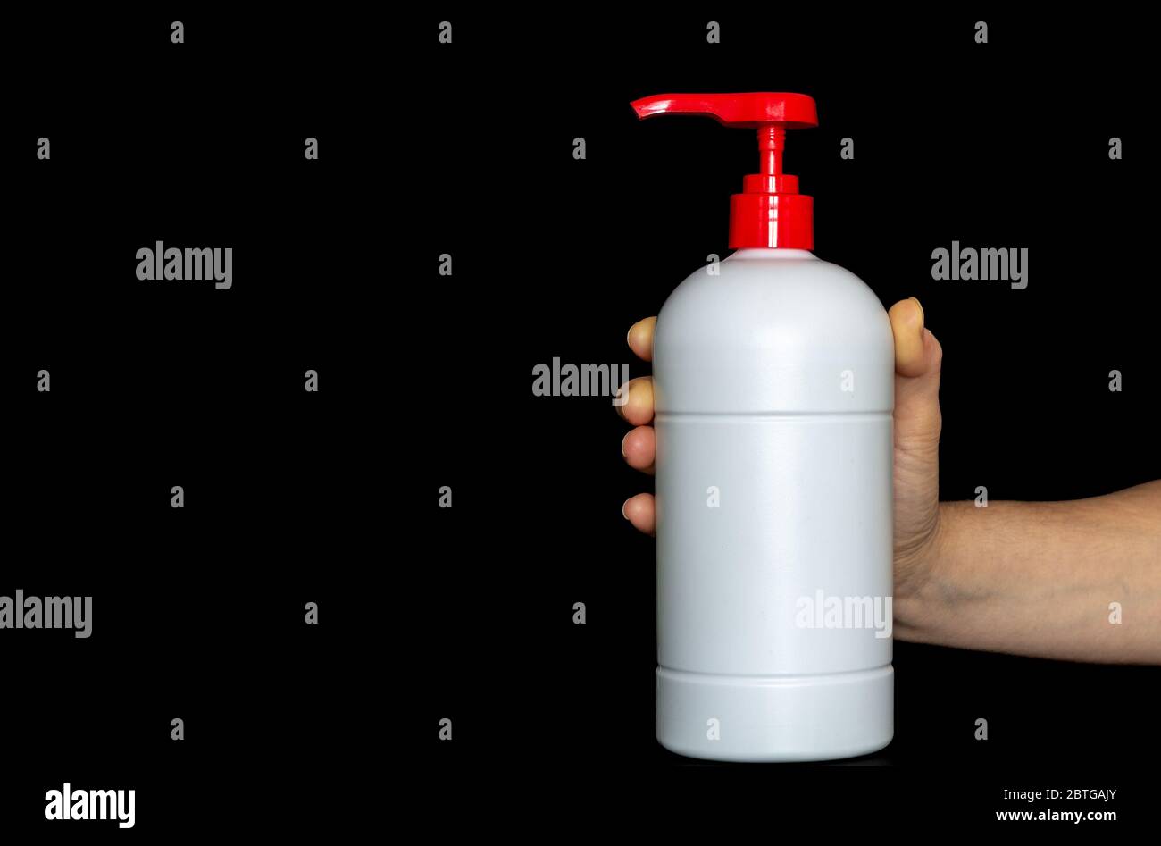 White plastic pushing pump bottle isolated on black background, woman is holding plastic bottle in her hand. Copy space advertising text area Stock Photo