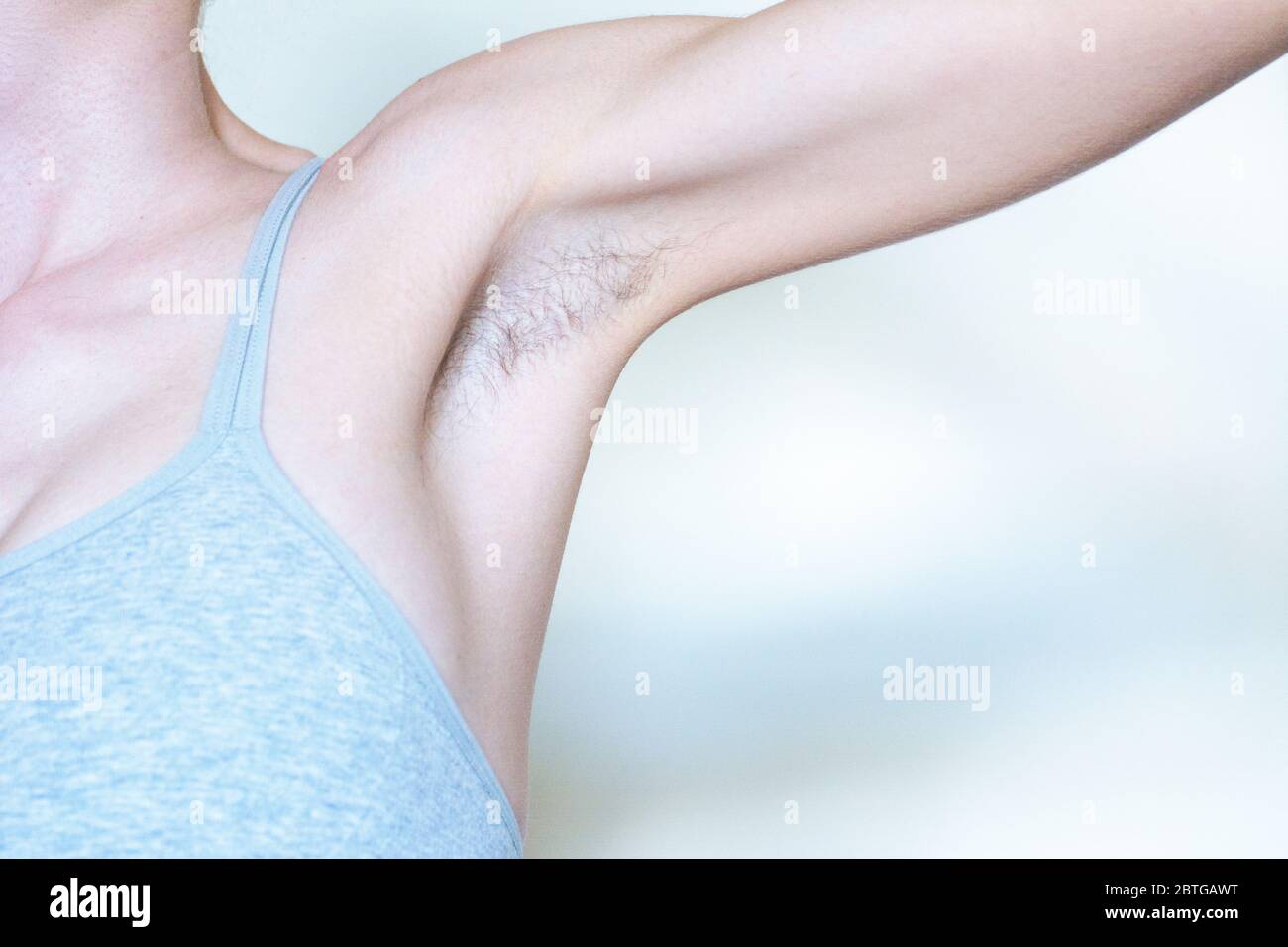 A woman displaying a hairy armpit before shaving it Stock Photo