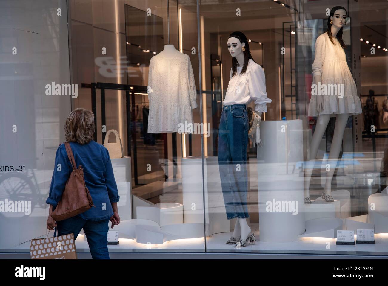 Barcelona, Spain. 25th May, 2020. A woman passing by an opened clothing  store from the downtown shopping area Portal del Angel in Barcelona, Spain  on 24th of May 2020. Starting today, the