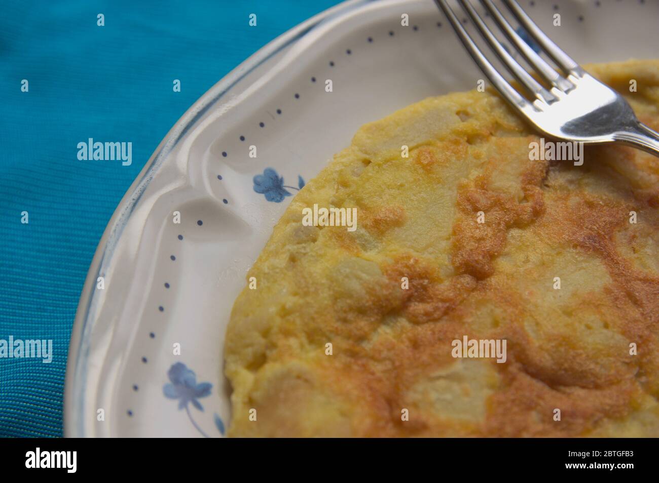 Closeup of a plate with a Spanish omelette or potato next to a fork ready to eat Stock Photo