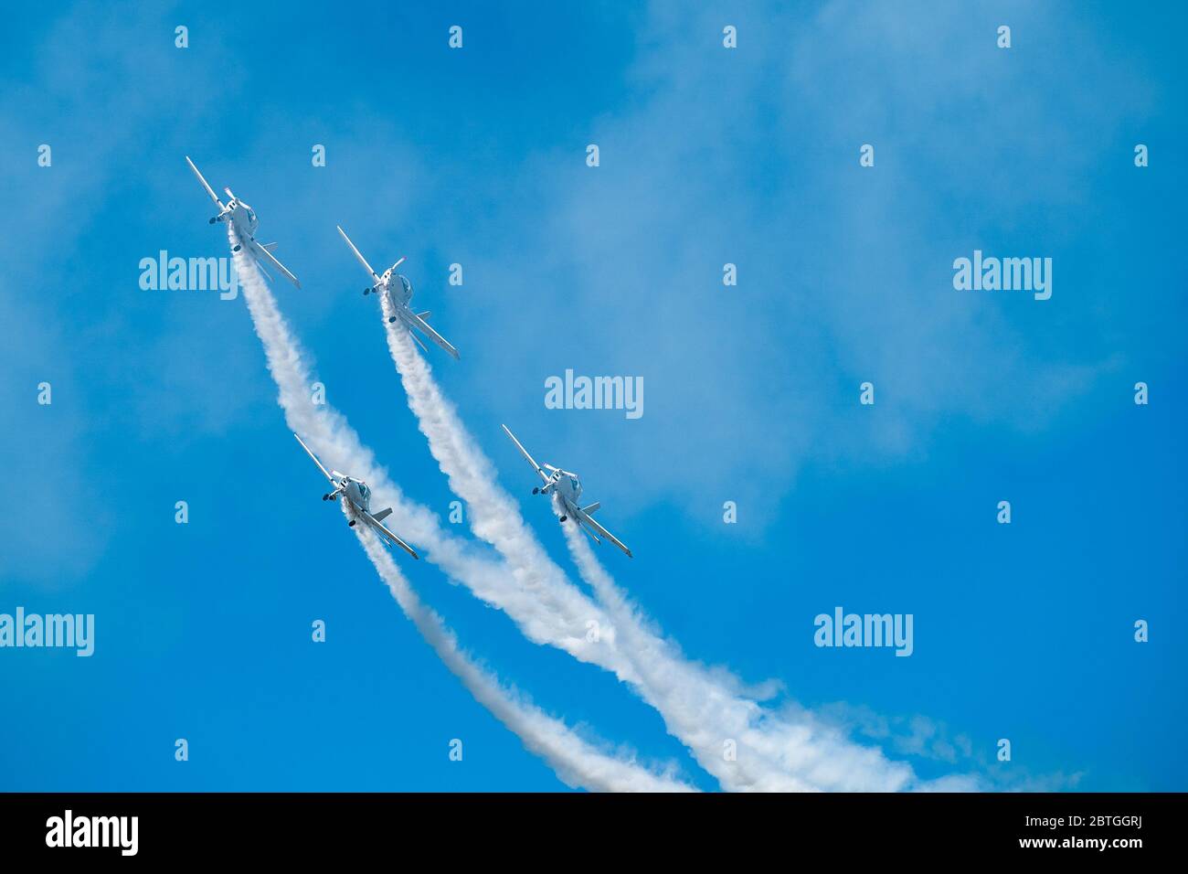 Airplanes with white smoke traces on air show. Pilots make tricks on jets at blue sky background. Stock Photo