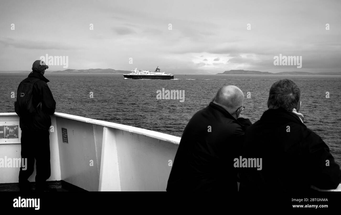 male on boat watching ferry go past Stock Photo