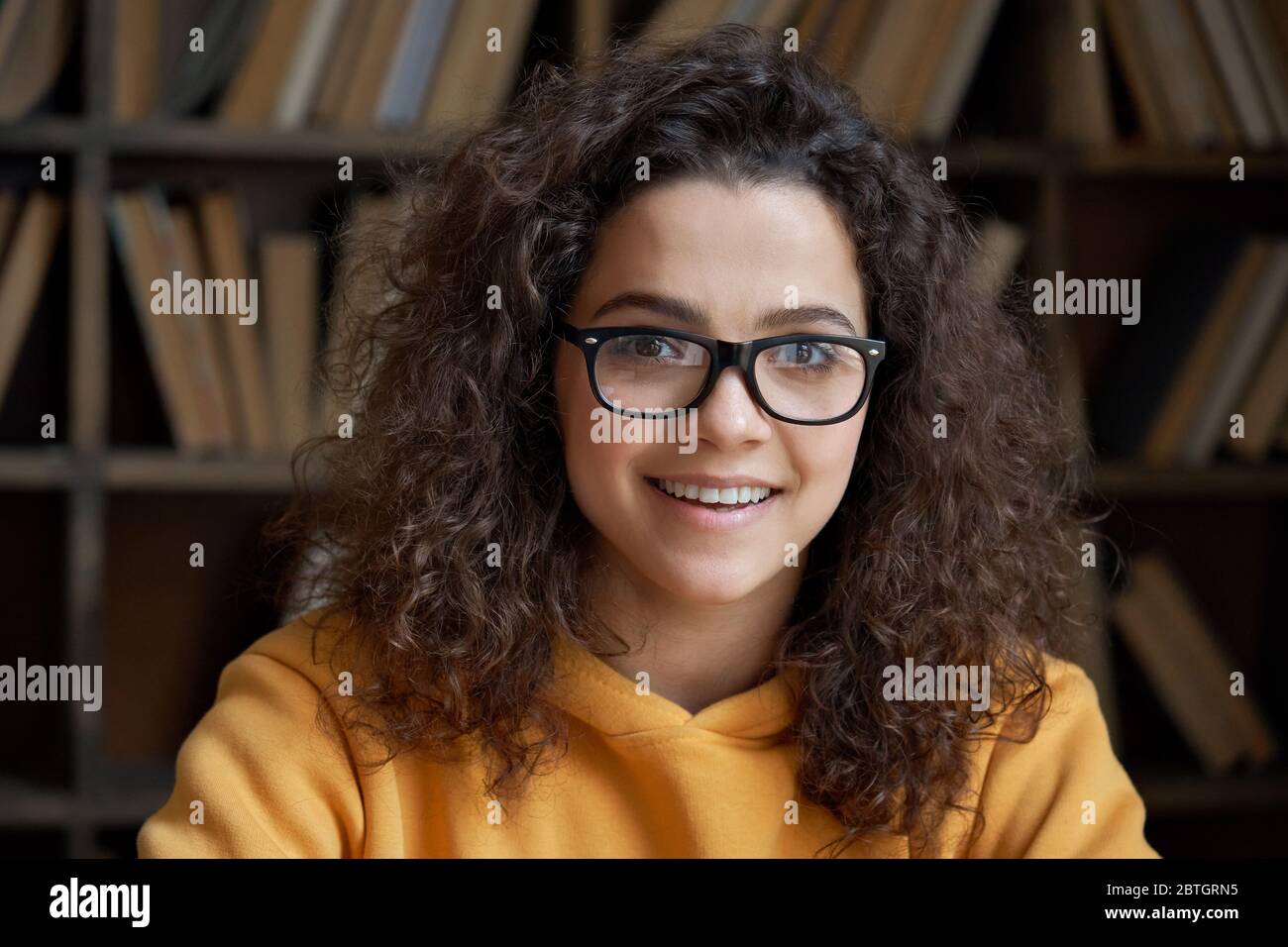 Smiling latin teen girl school student wear glasses looking at camera, headshot. Stock Photo