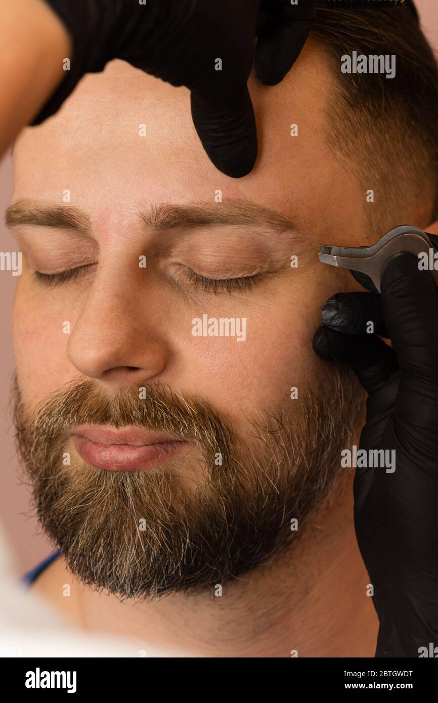 Professional barber doing threading procedure and correcting shape of