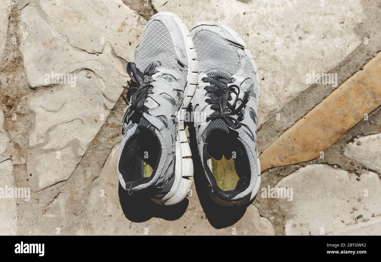 Old Running Shoes On Stone Surface Stock Photo