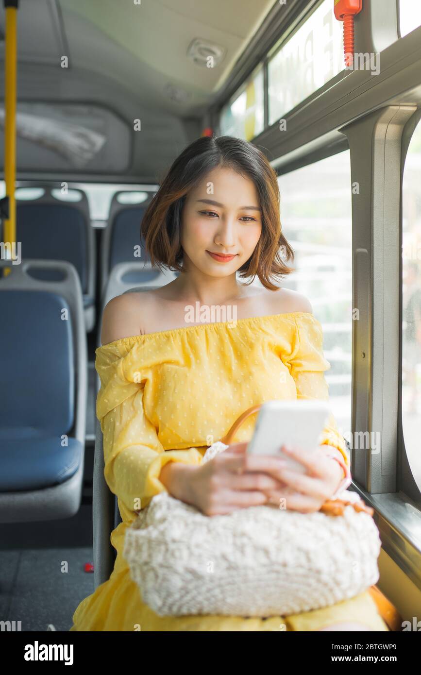 Beautiful woman using mobile phone when sitting on bus/ public transportation. Stock Photo