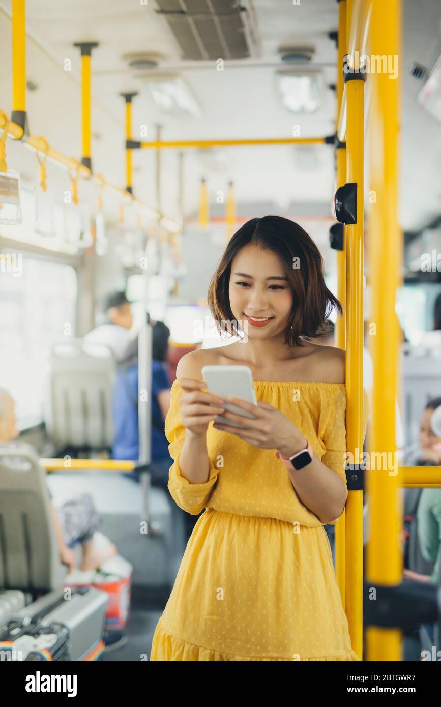 Young attractive woman using mobile while standing on the bus/ public transportation. Stock Photo