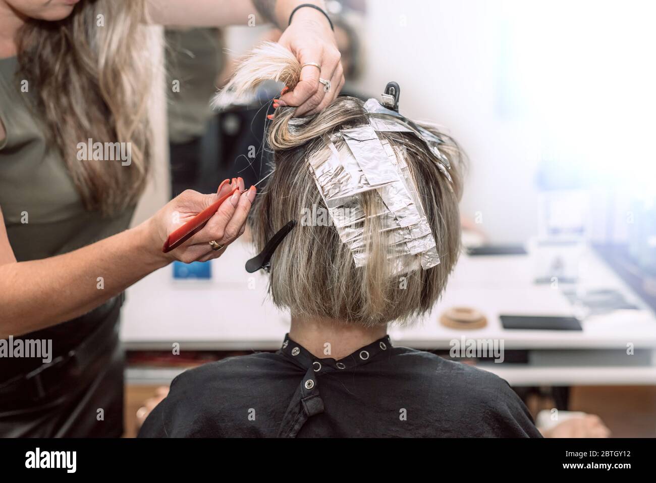 https://c8.alamy.com/comp/2BTGY12/master-hairdresser-in-beauty-salon-coloring-young-womans-hair-using-aluminum-foil-selective-focus-2BTGY12.jpg