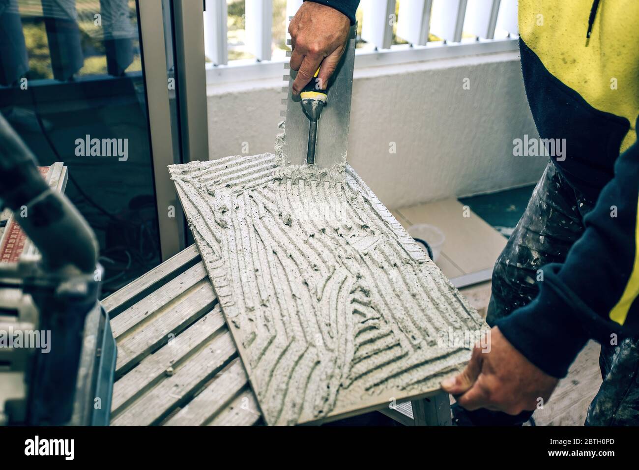 Professional builder smears cement glue on the ceramic tile with a