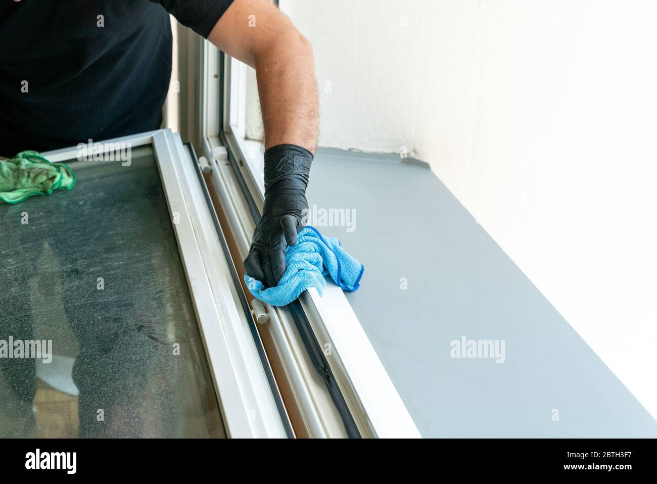 A profesional cleaner cleaning a dirty window frame with a micro fiber ...