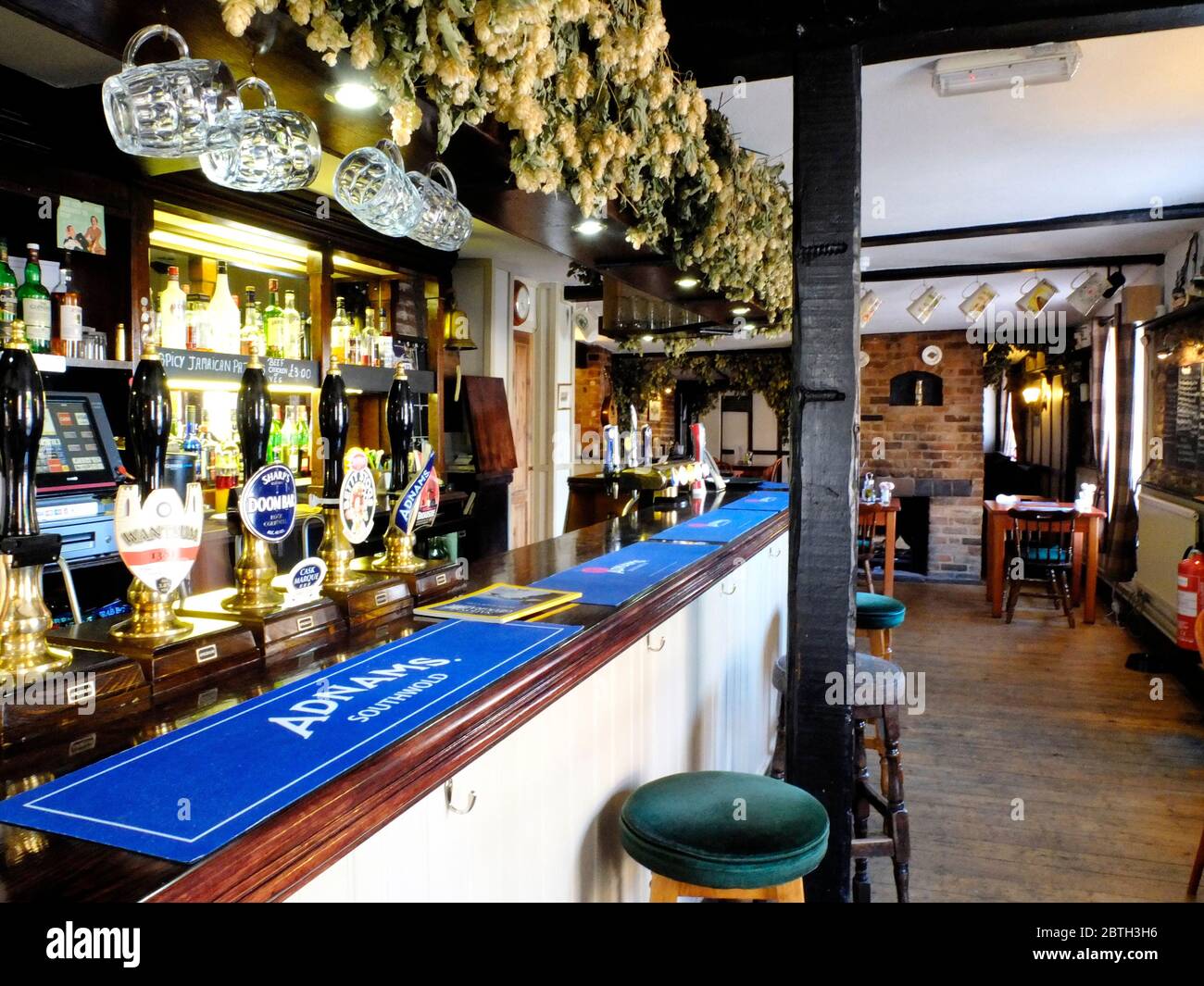 English pub interior showing bar, pint glasses, hops and barstools. Stock Photo