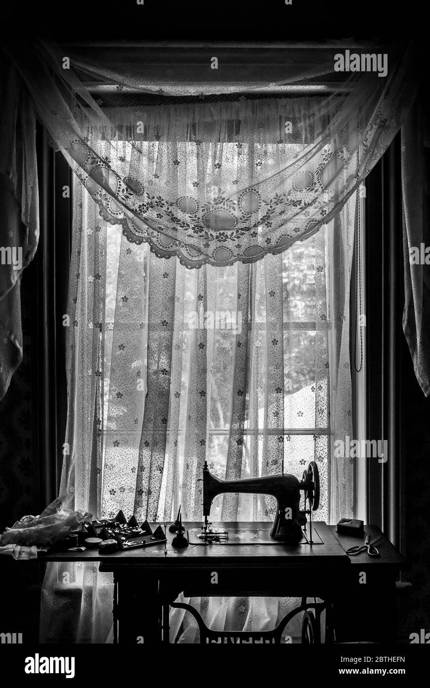 Sewing machine against a lace curtain in a traditional home Stock Photo