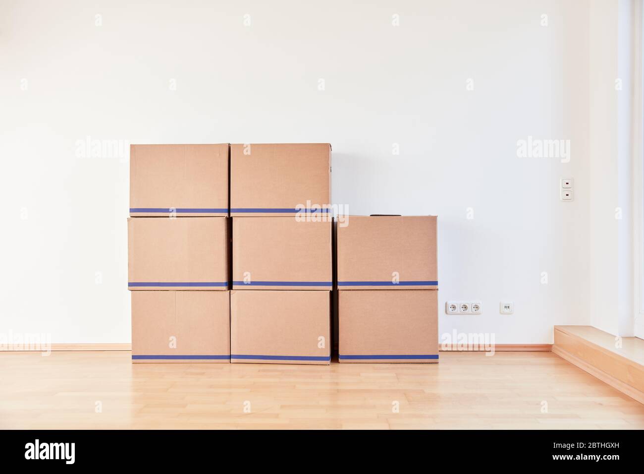 Many moving boxes stacked on the wall when moving to a new apartment Stock Photo
