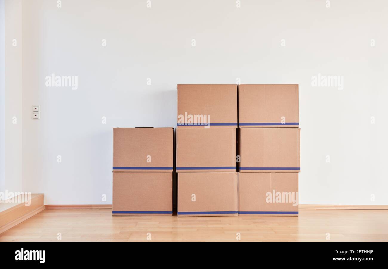 Many moving boxes are stacked in an empty room when moving with a freight forwarder Stock Photo