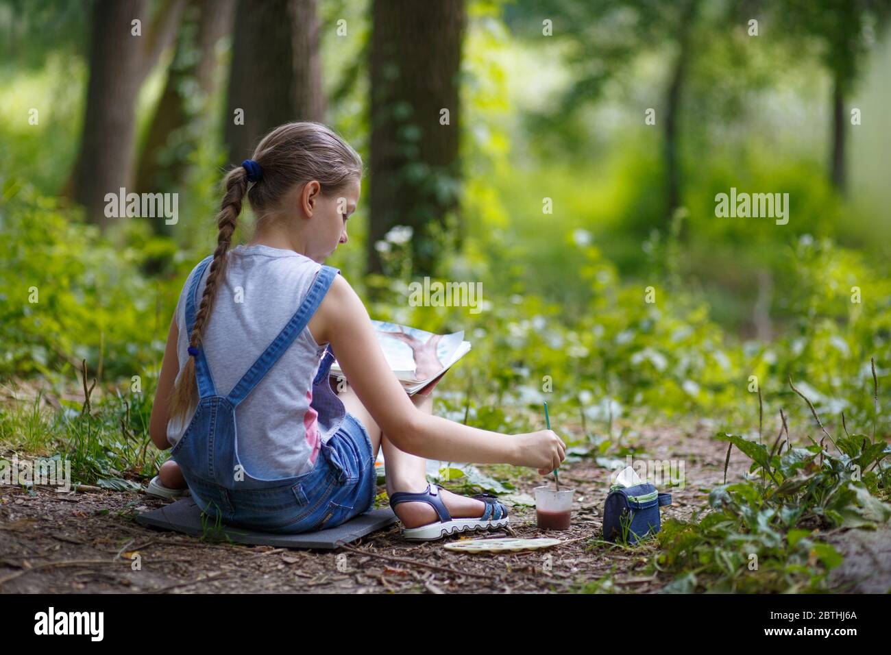 Girl painter paints trees in the park 