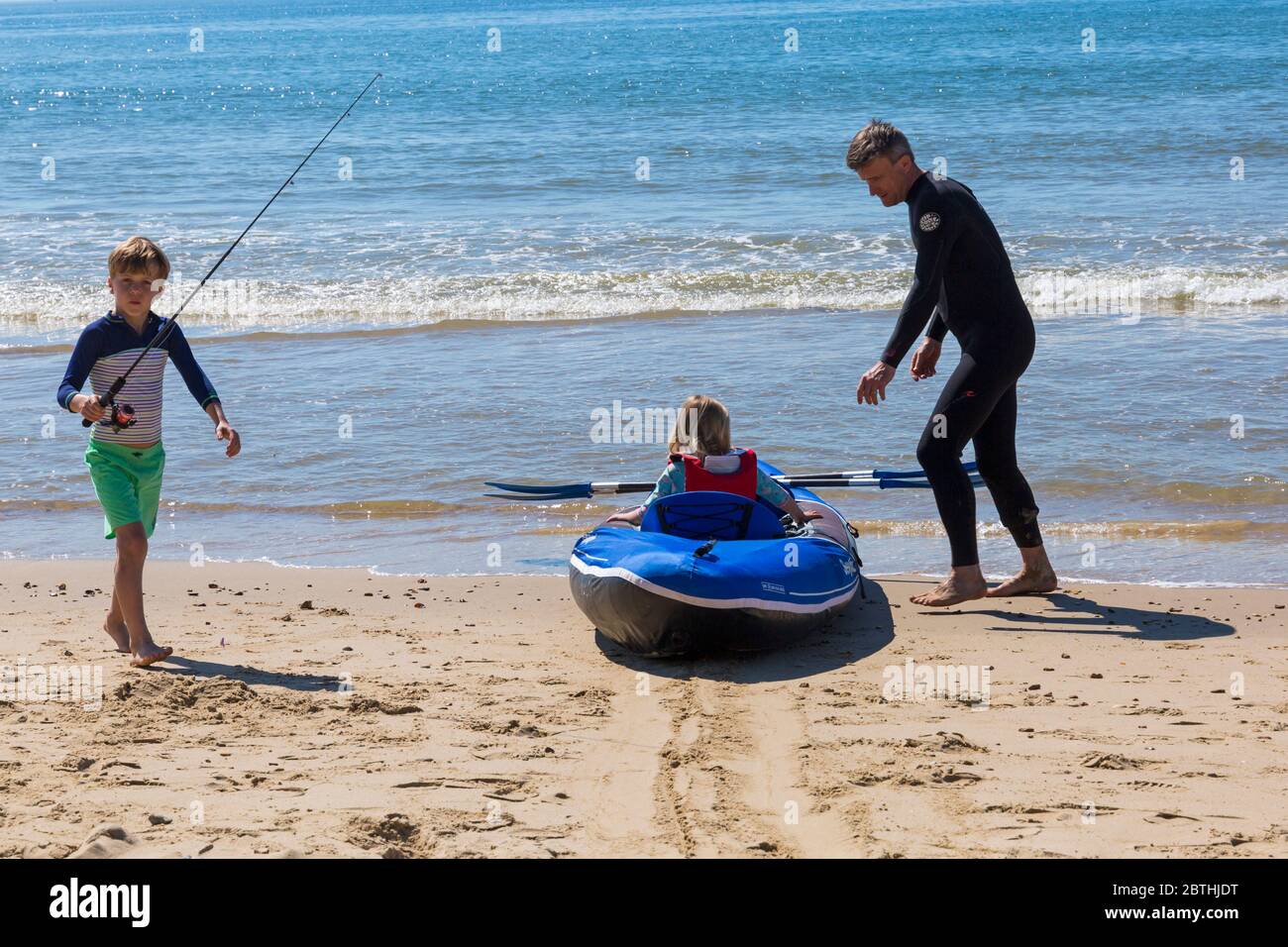 Bournemouth, Dorset UK. 26th May 2020. UK weather: another hot sunny day at Bournemouth beaches with clear blue skies and unbroken sunshine, as the glorious weather continues and temperatures rise. Sunseekers head to the seaside to enjoy the sunshine. Henry and Olivia, 6 and 5, go kayak fishing in the sea. Credit: Carolyn Jenkins/Alamy Live News Stock Photo