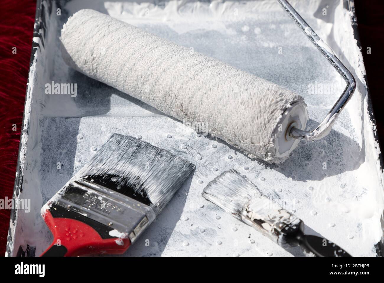 A roller and paint brushes in a paint tray. The are used to apply paint