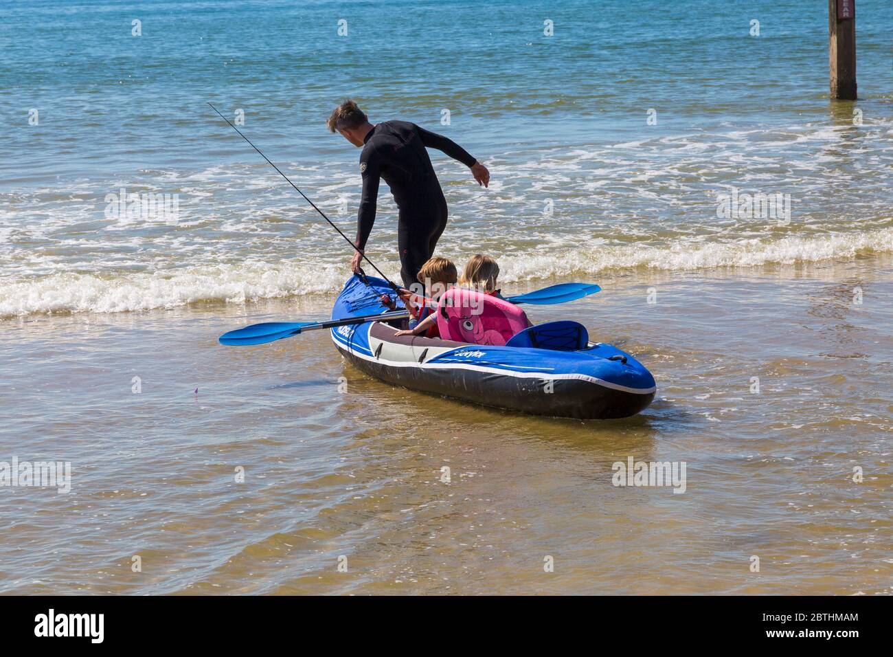Bournemouth, Dorset UK. 26th May 2020. UK weather: another hot sunny day at Bournemouth beaches with clear blue skies and unbroken sunshine, as the glorious weather continues and temperatures rise. Sunseekers head to the seaside to enjoy the sunshine. Henry and Olivia, 6 and 5, go kayak fishing in the sea.  Credit: Carolyn Jenkins/Alamy Live News Stock Photo