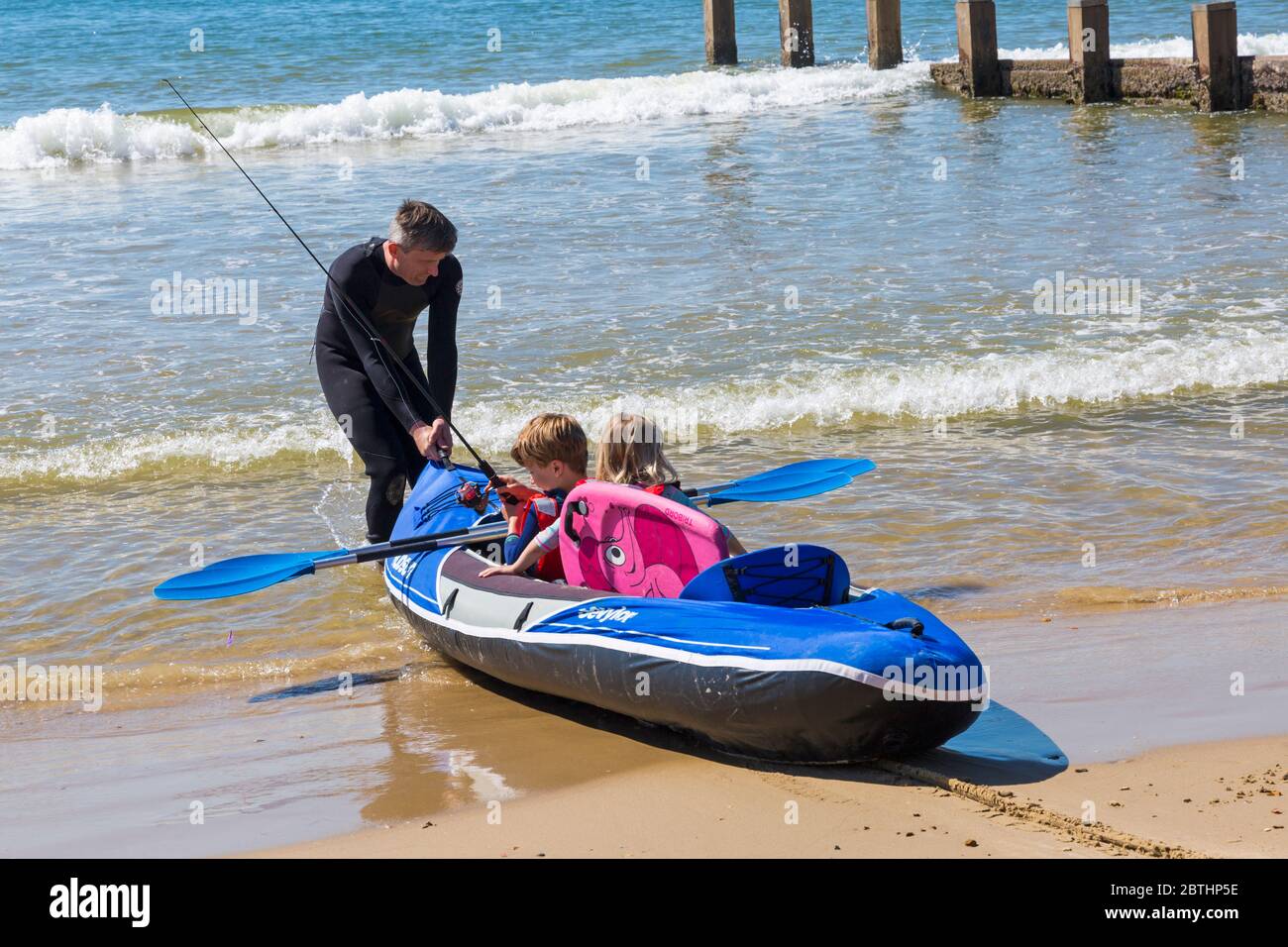 Bournemouth, Dorset UK. 26th May 2020. UK weather: another hot sunny day at Bournemouth beaches with clear blue skies and unbroken sunshine, as the glorious weather continues and temperatures rise. Sunseekers head to the seaside to enjoy the sunshine. Henry and Olivia, 6 and 5, go kayak fishing in the sea. Credit: Carolyn Jenkins/Alamy Live News Stock Photo