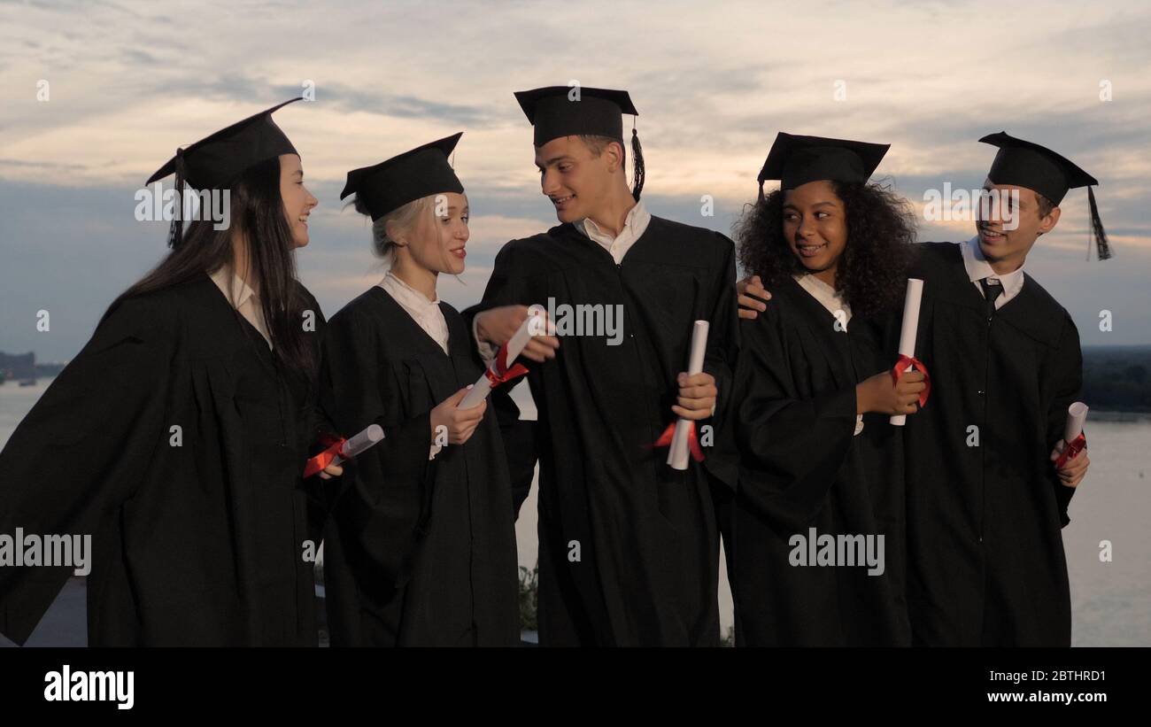 Group of happy graduates walking to graduation ceremony in the e Stock Photo