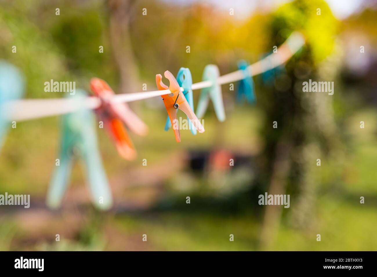 Orange and blue cloth clip on clothes line, blur nature green background Stock Photo